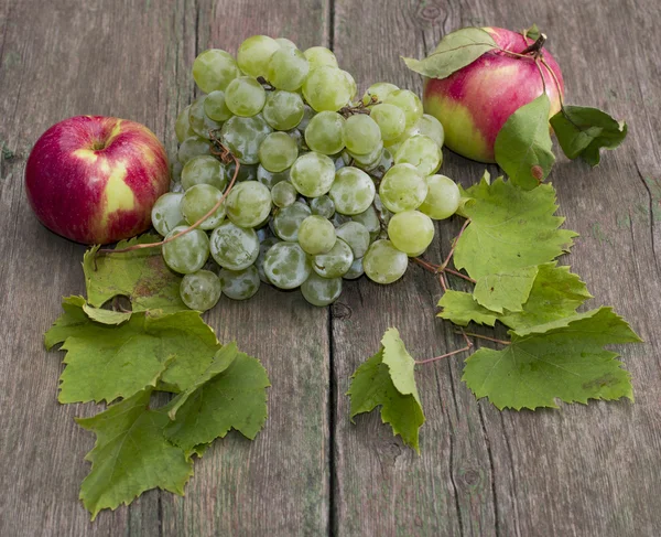 Grupo de uvas e duas maçãs de cada lado, em uma mesa velha — Fotografia de Stock