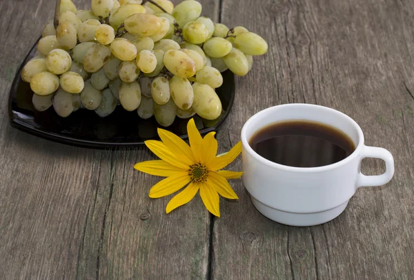 Plato con uvas, una taza de café y una flor amarilla, un bodegón —  Fotos de Stock