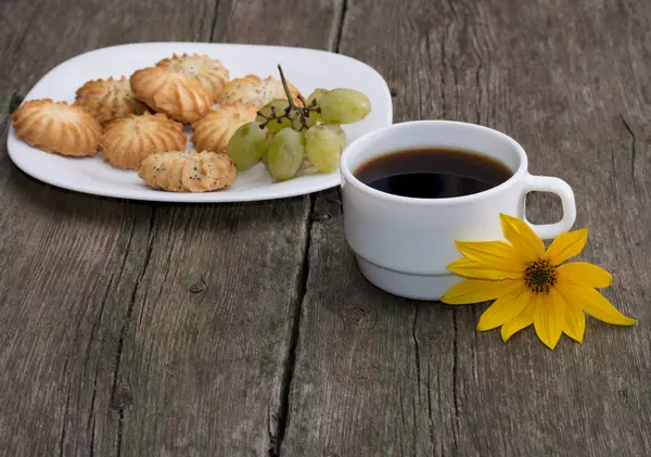 Plate with cookies, a cup of coffee and a yellow flower, a still — Stock Photo, Image