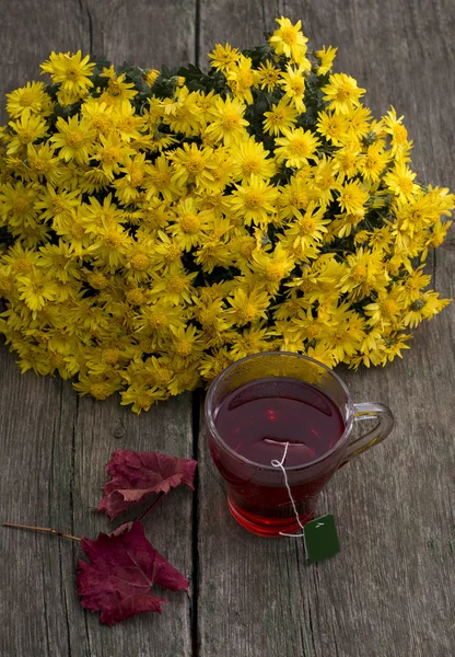 Натюрморт, букет желтых цветов, прозрачная чашка чая и — стоковое фото