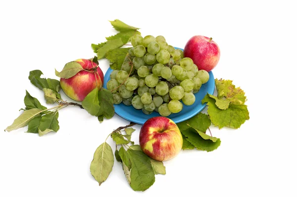 Uvas em um prato e três maçãs em volta, isolam — Fotografia de Stock