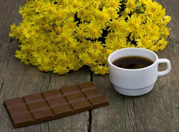 Bouquet von schönen Blumen, Schokolade und Kaffee, auf einem hölzernen — Stockfoto