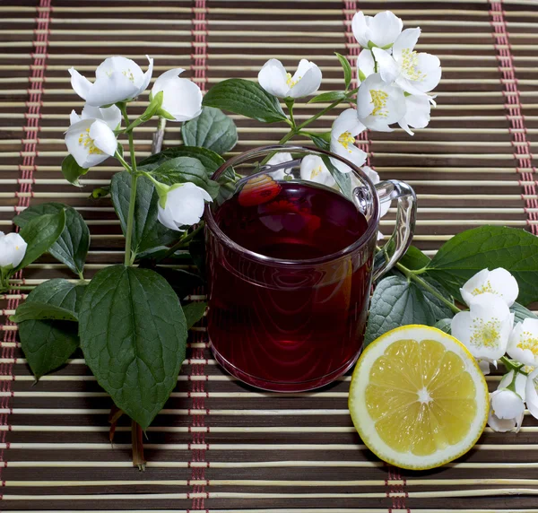 Mug of red drink, the cut lemon and flower, still life — Stock Photo, Image