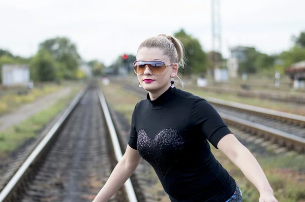 美丽的女人在铁轨上戴着太阳镜 — 图库照片