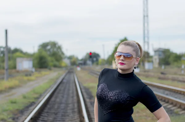 Portrait of the cheerful girl in sunglasses against railway trac — Stock Photo, Image