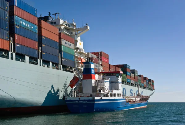 Nakhodka. Rusya - 06 Temmuz 2016: Bunkering tanker Zaliv'e Nakhodka bir büyük konteyner gemisi Cosco Pekin.