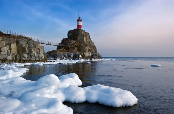 Winterbild Leuchtturm auf einem einsamen Felsen. — Stockfoto
