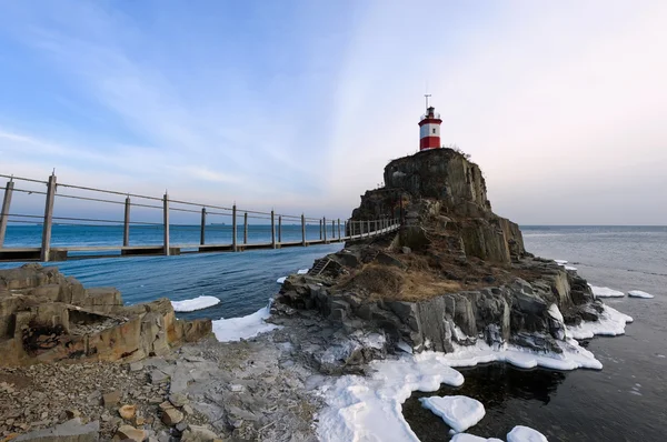 Winter picture lighthouse on a lonely rock. — Stock Photo, Image