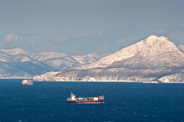 Buque de contenedores que se mueve por mar a lo largo de la costa del invierno montañoso. Bahía Nakhodka. Mar del Este (Japón). 02.01.2013 — Foto de Stock