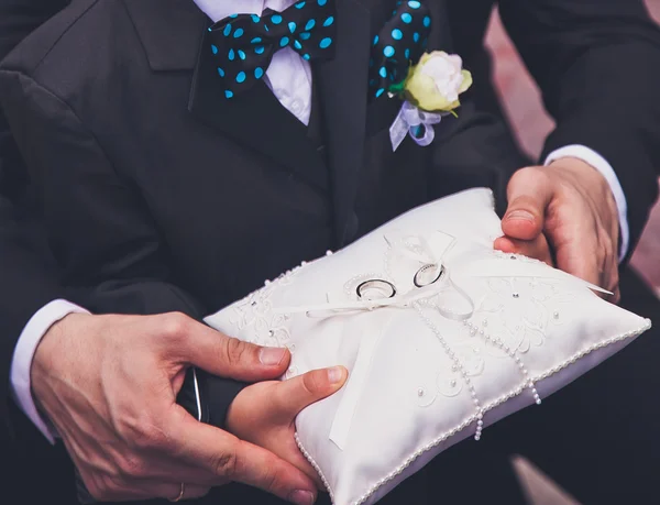 Niño y su padre entregando almohada con dos anillos de boda en ella. Ceremonia boda foto — Foto de Stock