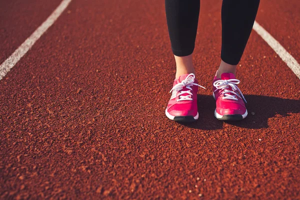 Jambes de femme en vêtements de sport et chaussures de course debout sur la piste de course — Photo