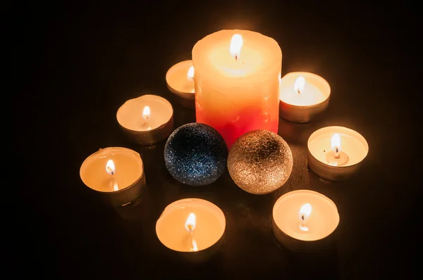 Petites bougies autour d'une bougie plus grande et deux globes de Noël — Photo