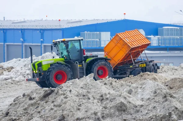 トレーラー付きの強力なトラクターは 街の通りからインストールの雪融けクラスターに雪を輸送します — ストック写真