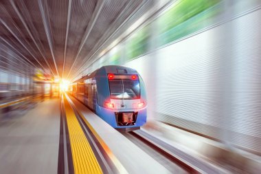 Çatıdaki tünel istasyonunda hareket bulanıklığı olan yüksek hızlı kırmızı tren ve insanlar için banklar.