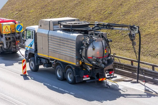 Sludge washer truck suction machine and workers specialists at work on the side of the highway to clean underground infrastructure, eliminate blockages in the sewer road sewage into the collector — Stock Image Sludge Washer Truck Suction Machine Workers Specialists Work Side Highway Royalty Free Stock Photos