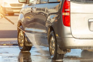 Yüksek güçlü püskürtme tabancasıyla minibüsü elle yıkamak.