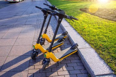 Otoparkta arka arkaya elektrikli scooterlar. Şehir bisiklet kiralama sistemi, sokakta halka açık scooter 'lar.