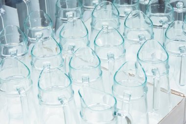 Bir mağazadaki rafta bir sürü yeni cam sürahi, satılık ev aletleri.