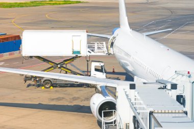 Yolcu uçağının yanındaki sarı kamyon, uçuş öncesi havaalanı.