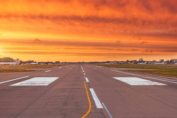 The runway is free ready for takeoff and landing of the aircraft, against the background of the brightest sunset with the textured striped clouds of red light