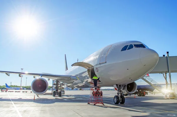 Airplane after landing with an open luggage compartment, against the background of the bright sun in the blue sky