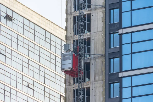 建設中の複数階建ての建物のファサードの外の建設エレベーター — ストック写真
