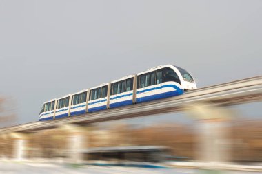 Hava köprüsündeki yüksek hızlı metro treni şehir sokaklarında yüksek hızda yol alır.