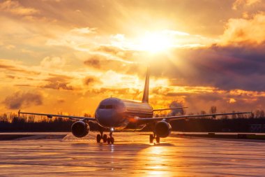 Hava alanındaki uçak, akşam yağmurundan sonra gün batımının altında dramatik bir gökyüzü.