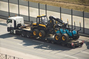 Ağaç gövdelerinin işlenmesi için gerekli ekipman nakliyesi. İleri makineler. Kamyon karavanının kargo platformunda kereste endüstrisi.