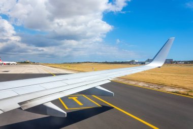 İniş taksisi ile havaalanı arasında makina kanadı olan bir jet uçağı penceresi görüntüsü