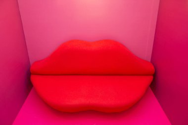Kırmızı dudaklar şeklinde kırmızı pembe bir odada kanepe.