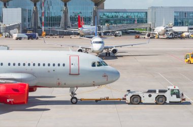 Havaalanındaki çekici uçağını geri çek, havaalanı terminaline bak diğer uçaklar, tipik havacılık işi