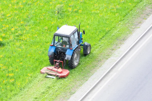 トラクターは 都市の芝生に草を刈るためにトレイル芝刈り機を使用し 空中ビュー — ストック写真
