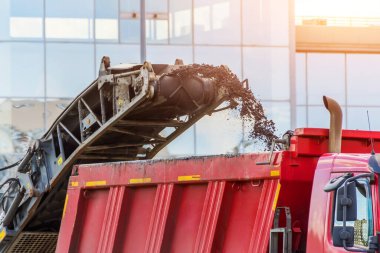Yol soğuk değirmen makinesi eski asfaltı kaldırır ve bir çöp kamyonuna yükler. Yolun asfalt kaldırımının tamiri