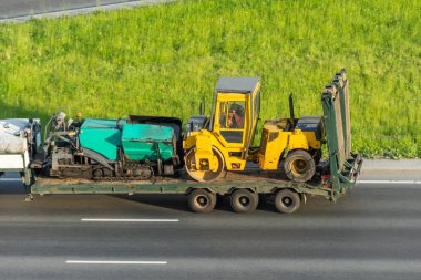 Kargo platformunda yük vagonunun yanındaki yol silindirini ve asfalt patikasını taşıyorum.