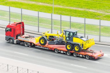 Şehirdeki otobanda uzun bir karavan platformu olan nakliye karavanının traktörü.