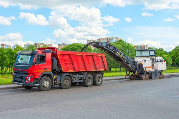 Road cold milling machine removes the old asphalt and loading into a dump truck. Repair of asphalt pavement of the road