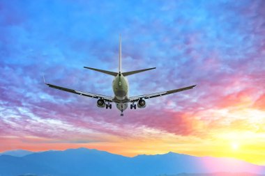 Güzel bir günbatımında dağların üzerinde uçan uçak