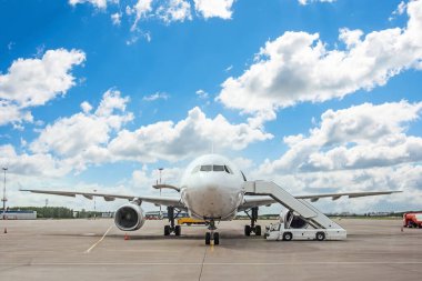 Güzel bir gökyüzünün zeminine iskelede park etmiş bir uçak.