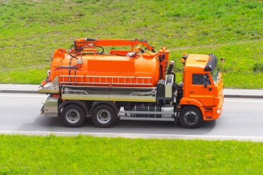 Tankı ve su pompalama sistemi olan turuncu bir kamyon otoyolda ilerliyor.