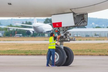 Jet motoru havacılık teknisyeni pistte ticari bir uçağın yanında poz veriyor.