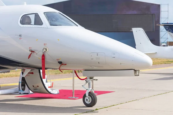 Business jet with open door and red carpet, view of the nose and cockpit of the airplane