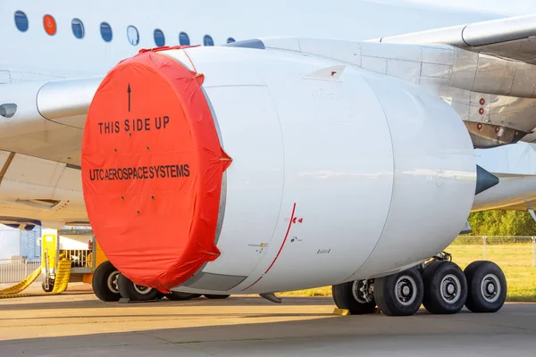 Test aircraft with a red cover on the engine under the wing in a parking lot