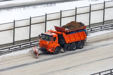 Kar küreme aracı soğuk bir kış gününde karayolunu kardan temizliyor.