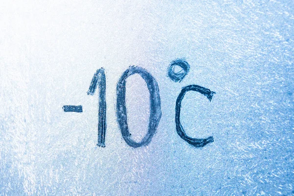 14 degrees Fahrenheit or -10 Celsius number lettering on icy glass covered with ice and frost. The concept of extreme cold weather