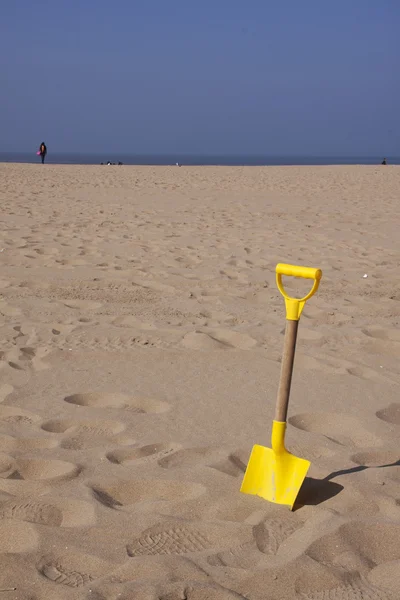 Beach shovel standing upright in the sand o the beach Royalty Free Stock Photos