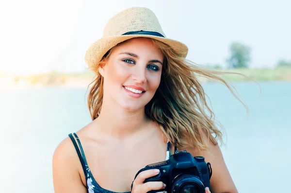 Retrato de mujer joven con sombrero en la playa con cámara — Foto de Stock