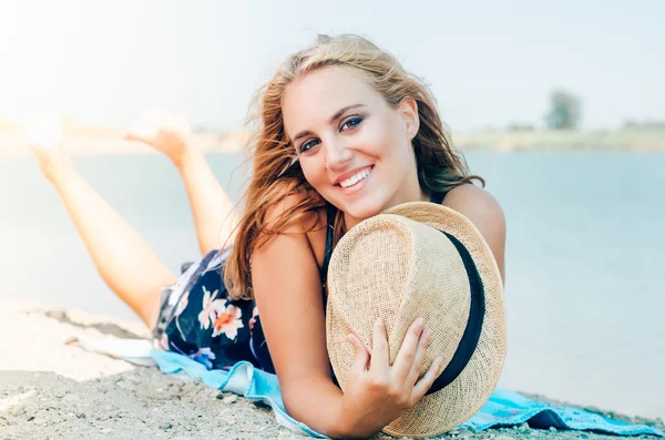 Jonge lachende vrouw met hoed op het strand — Stockfoto