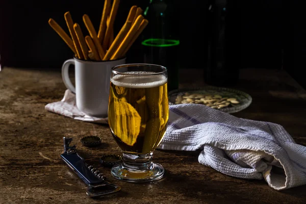 Glas light bier op een donkere bruin tafel met snacks — Stockfoto