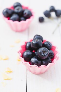 Hafif ahşap kurullarında pembe kek meyve chokeberry.